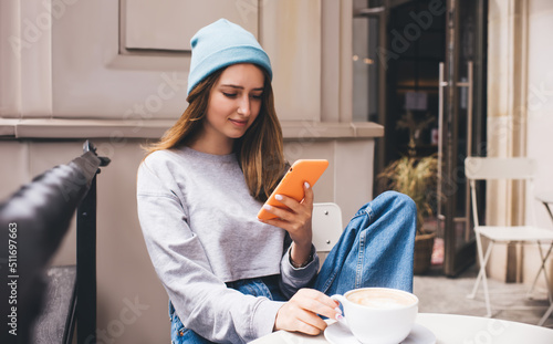 Young millennial female using social network application on mobile phone for communication. Caucasian hipster girl holding smartphone in silicone case. Teenager browsing online with internet data photo