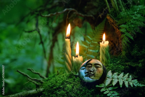 candles and symbolic moon amulet on dark forest background. pagan Wiccan, Slavic traditions for Litha. Witchcraft, esoteric spiritual ritual, magic practice. Mysticism, divination, modern occultism photo