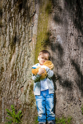 A cute boy is playing with a bear cub in the forest. The sun's rays envelop the space. A magical story of interactions for the book. Space for copying.