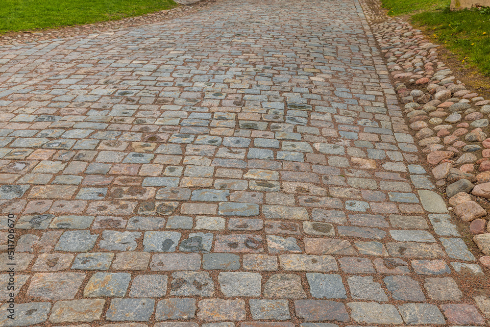 Beautiful view of pavement in park lined with old cobblestones. Sweden.