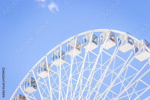 Ferris wheel on a blue sky. Amusement park. Empty ferris wheel on sunny day in Kyiv, Ukraine. Summer recreation. Leisure activity. Big circle Vintage carousel on blue sky. Outdoors attraction.