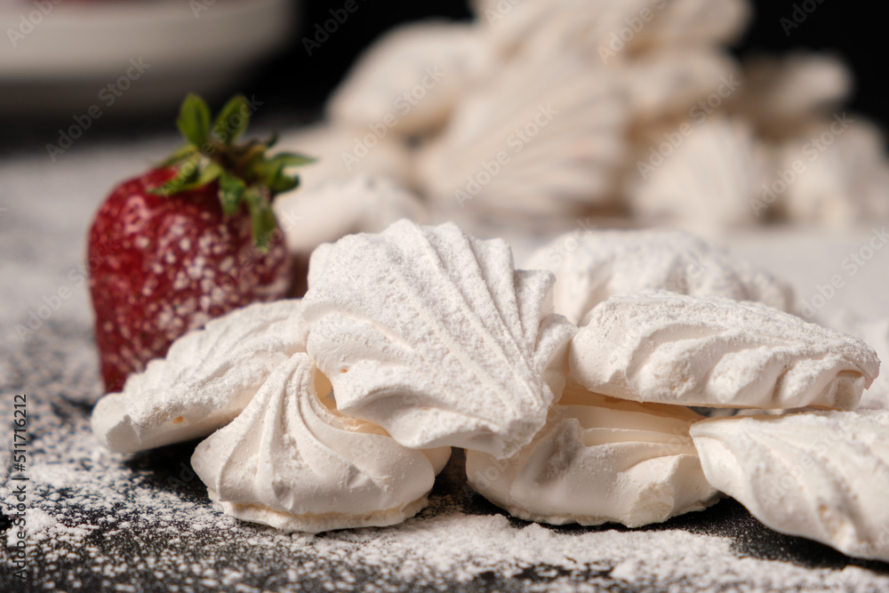 Airy meringues and strawberries on powdered sugar.