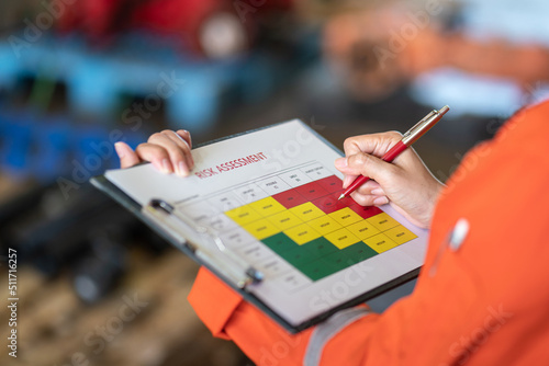 Action of a person is using ballpoint pen to marking on the risk assessment matrix table at 