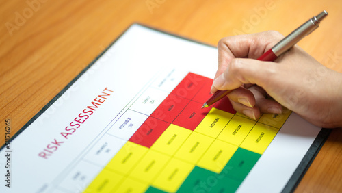 Fotografi Action of a person is using ballpoint pen to marking on the risk assessment matrix table at High risk level