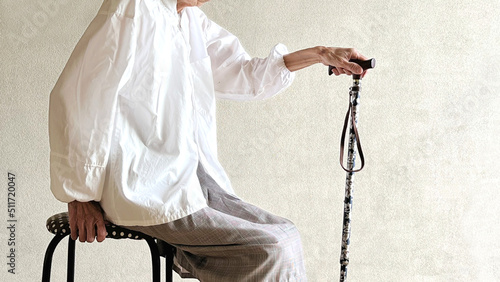 椅子に座って杖を持つ高齢女性