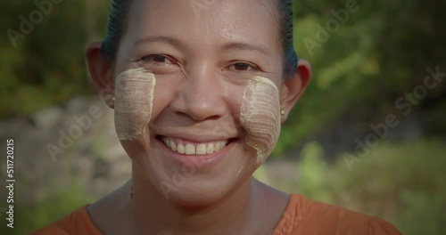 A happy smiling Burmese female farmer woman who powder to their cheeks, known as 