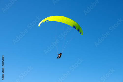 The sportsman flying on a paraglider. Silhouette on blue sky. Paragliding take off. Travel destination. Summer and holiday concept. 