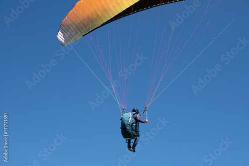 The sportsman flying on a paraglider. Silhouette on blue sky. Paragliding take off. Travel destination. Summer and holiday concept. 
