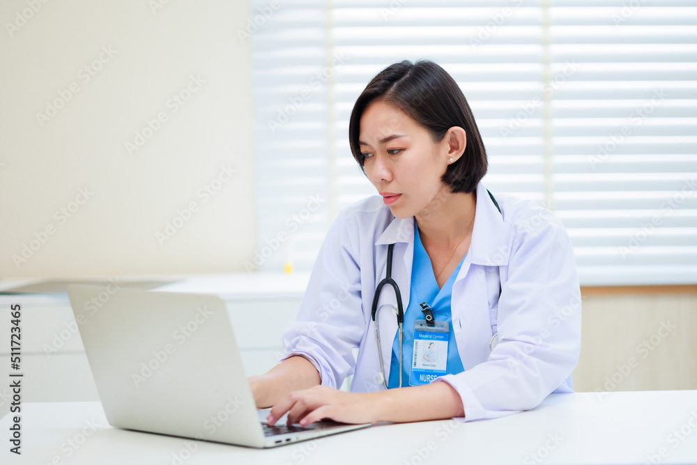 Working on laptop. Female asian doctor sitting on desk office at modern medical center. Healthcare medical and medicine concept. Working on laptop. Female asian doctor sitting on desk office at modern medical center. Healthcare medical and medicine concept.