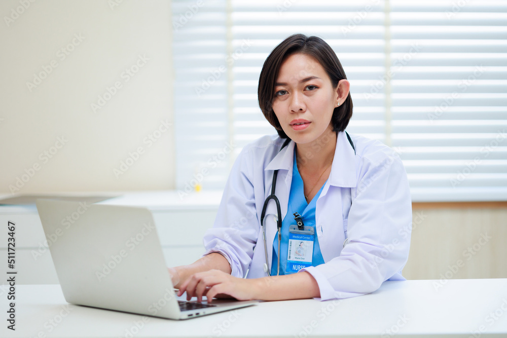 Working on laptop. Female asian doctor sitting on desk office at modern medical center. Healthcare medical and medicine concept. Working on laptop. Female asian doctor sitting on desk office at modern medical center. Healthcare medical and medicine concept.