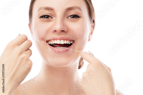 Smiling woman using tooth floss cleaning and caring for perfect teeth posing on isolated white background. Teeth Flossing. 