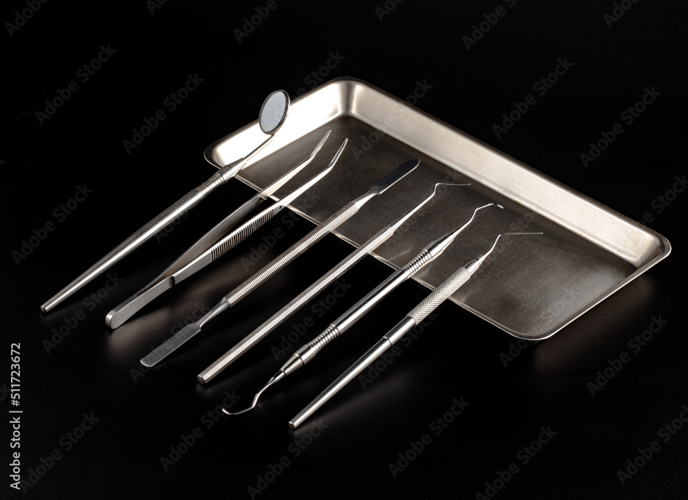 Set of dental metal instruments for treating and checking teeth. Top view on black background Set of dental metal instruments for treating and checking teeth. Top view on black background
