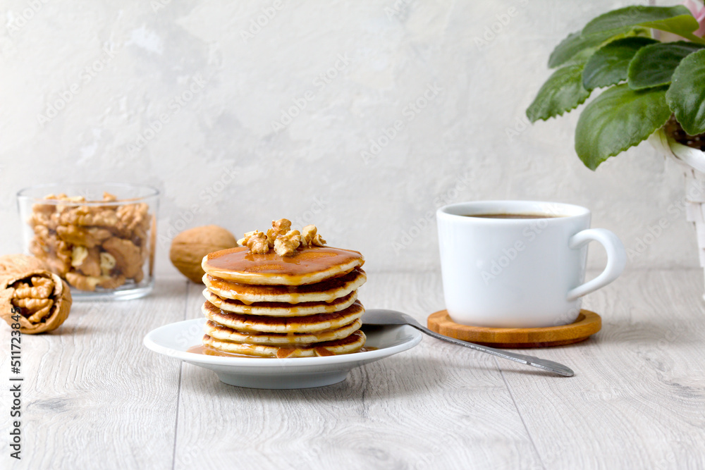 a stack of delicious pancakes poured with syrup, with walnuts and a cup of aromatic coffee. delicious healthy breakfast a stack of delicious pancakes poured with syrup, with walnuts and a cup of aromatic coffee. delicious healthy breakfast
