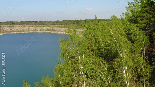 Picturesque nature of Ukrainian quartz quarry. Aerial footage of artificial pit with crystal clear water surrounded with lush forest. High quality 4k footage photo