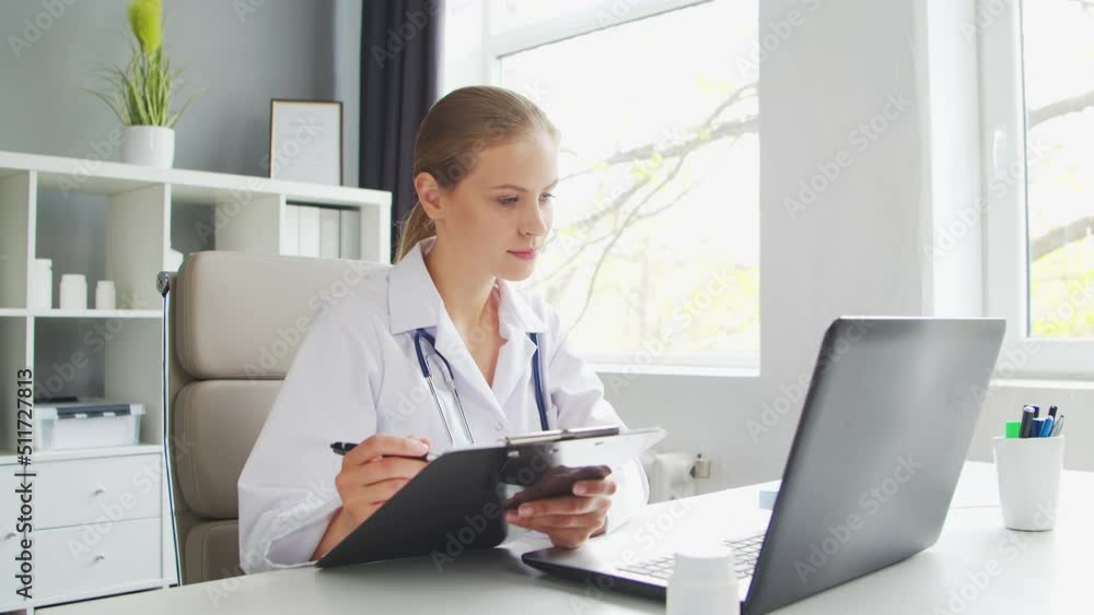 Doctor Works in the Medical Office. Woman in White Coat. Workplace of a Professional Female Therapist in a Hospital or Clinic. Healthcare and Medicine. Doctor Works in the Medical Office. Woman in White Coat. Workplace of a Professional Female Therapist in a Hospital or Clinic. Healthcare and Medicine.