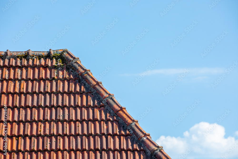 View of old tile roof against blue sky