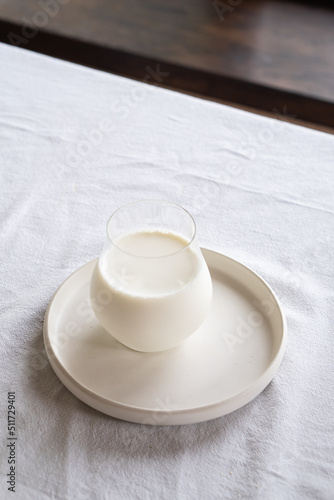 A glass of milk on a light plate on a table with a white tablecloth