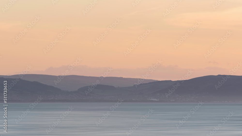 Stunning landscape image of pastel color sunset over ocean giving lovely soft dreamy relaxing feel