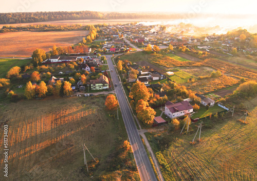 Suburb houses in rural, aerial view. Autumn season.. Roofs of suburban houses in rural. Suburb houses and rural buildings in fall colors on sunset. Farm house at agriculure field photo