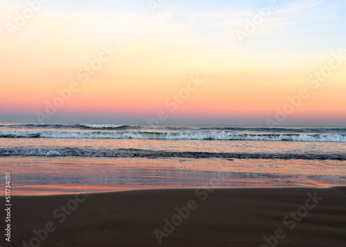Waves in sea on sunset background. Waves in sea during storm and wind. Wave from the sea goes on land to the beach. Splashing Waves in ocean  background  texture. Wave at Rising Storm. Seashore.