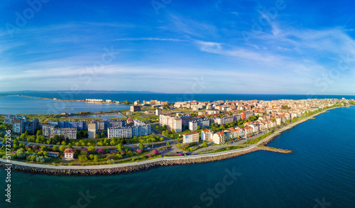 Panorama on promenade with people walking near Black Sea against backdrop of town Pomorie in Bulgaria under a cloudy sky