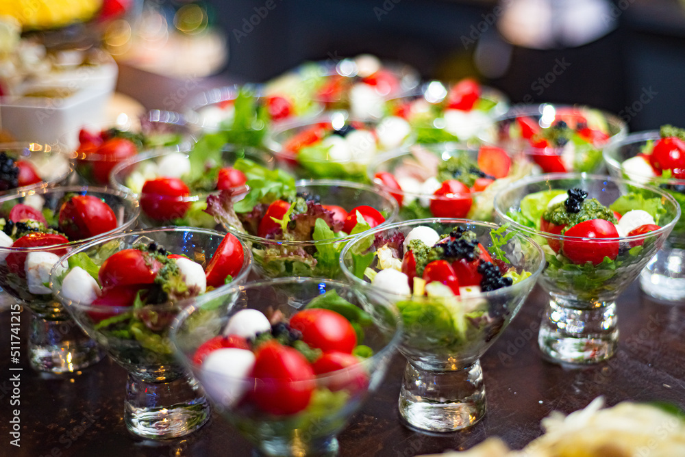Small cocktail servings of cherry tomato salad, mozzarella balls, lettuce Lollo Rosso. Lots of portions in a glass serving. Catering Layout. Small cocktail servings of cherry tomato salad, mozzarella balls, lettuce Lollo Rosso. Lots of portions in a glass serving. Catering Layout.