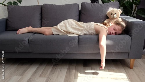 Cute little preteen girl sleep dream nap on cozy couch lying in comfortable pose with closed eyes. Tired tween child kid asleep on comfy sofa in silent light living room after active day. Sweet dreams