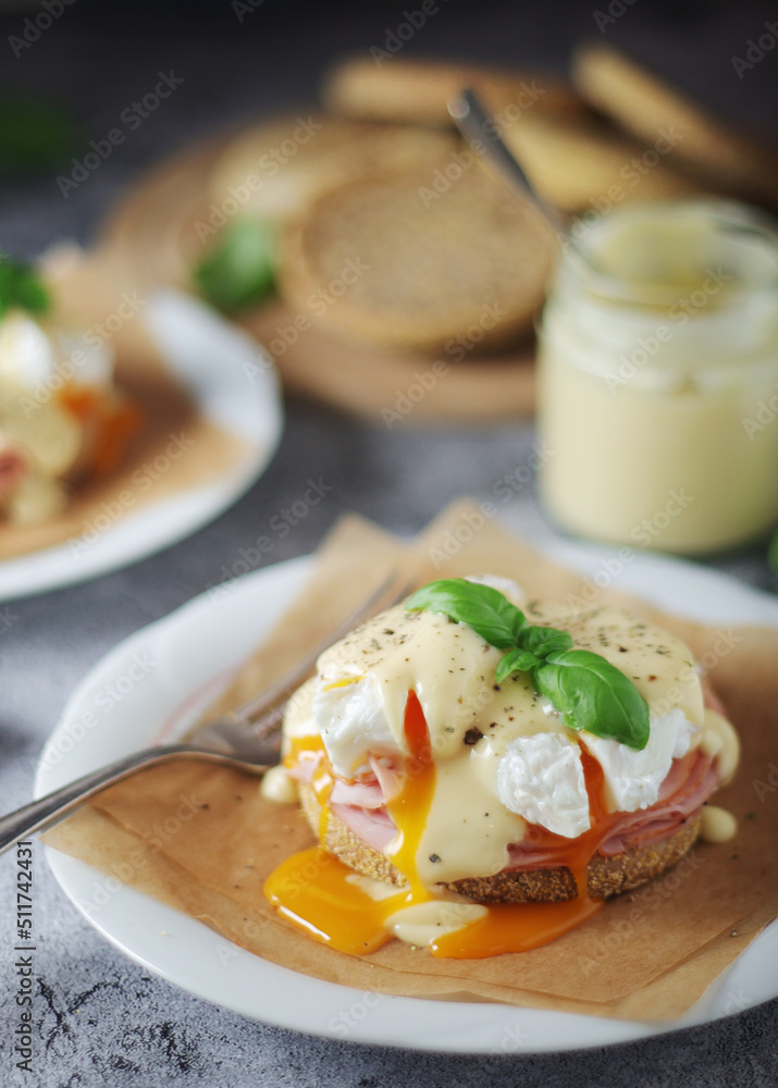Egg benedict sandwiches - muffin with poached egg, ham and hollandaise sauce Egg benedict sandwiches - muffin with poached egg, ham and hollandaise sauce