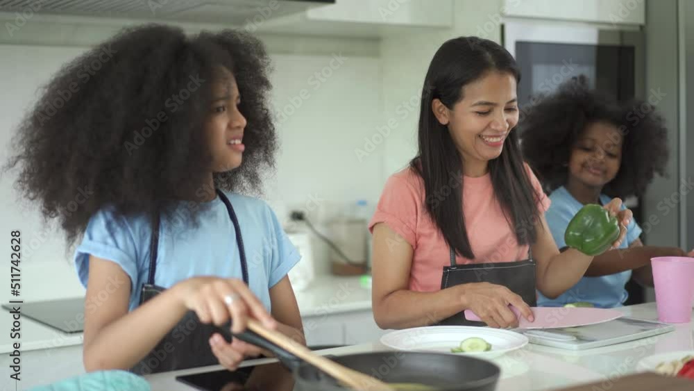 Happy family cooking together, mother teaching and helping her daughters to cook in a kitchen. Happy family cooking together, mother teaching and helping her daughters to cook in a kitchen.