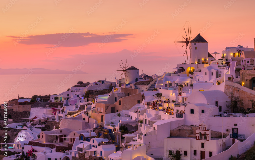 Fototapeta Oia village, Santorini, Greece. View of traditional houses in Santorini. Small narrow streets and rooftops of houses, churches and hotels. Landscape during sunset. Travel and vacation photography.