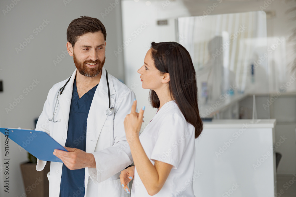 Obraz premium Doctor and nurse solve work issues standing near reception in clinic