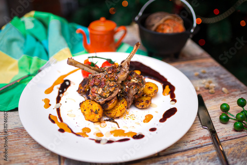 rack of lamb with baked mini potatoes on a plate covered in drops of souse