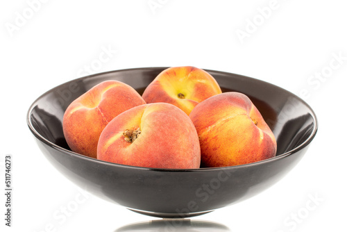 Several sweet organic peaches with a black ceramic plate, close-up, isolated on a white background.