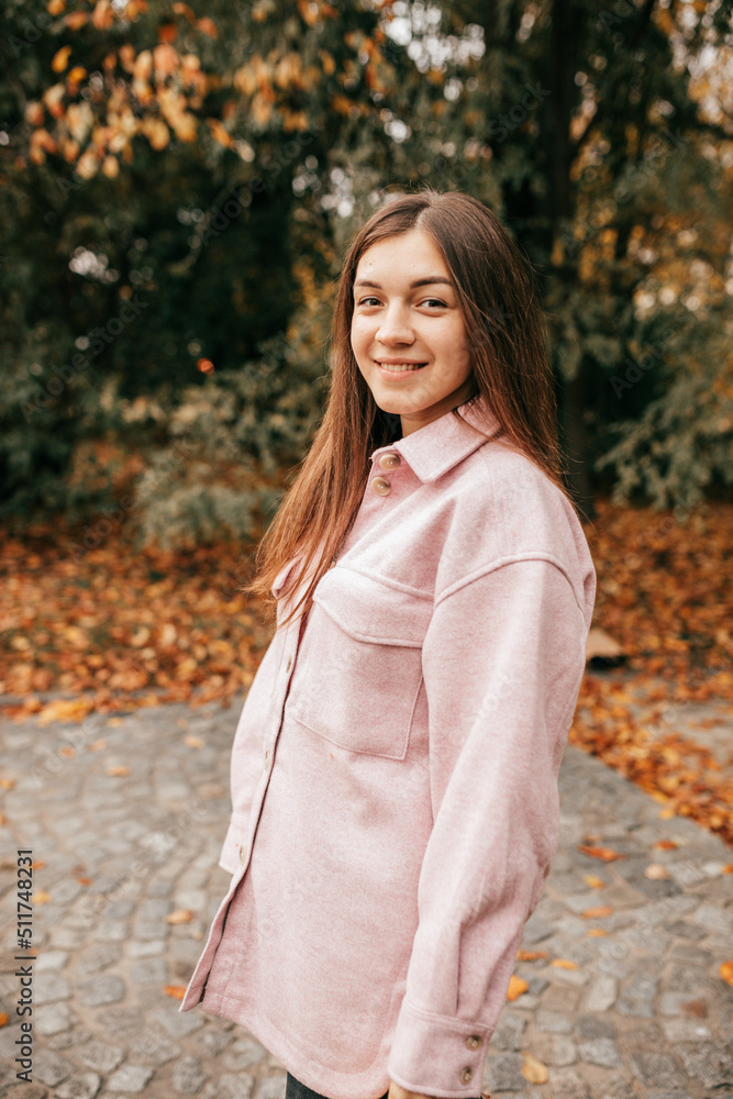 Charming brown-haired woman walking on warm autumn day in city square looks happy and peaceful. She is wearing warm soft pink shirt. Weekend. Lifestyle. Walking in fresh air. Charming brown-haired woman walking on warm autumn day in city square looks happy and peaceful. She is wearing warm soft pink shirt. Weekend. Lifestyle. Walking in fresh air.