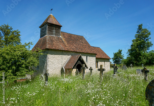 Pretty village church viewed from overgrown churchyard. Small rural church exterior in picturesque location in England UK