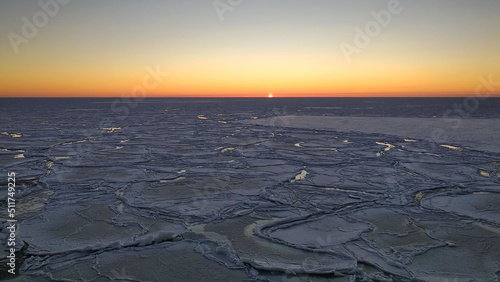 Northern uninhabited landscapes. Ice floes on the winter Barents Sea and a colorful sunset.