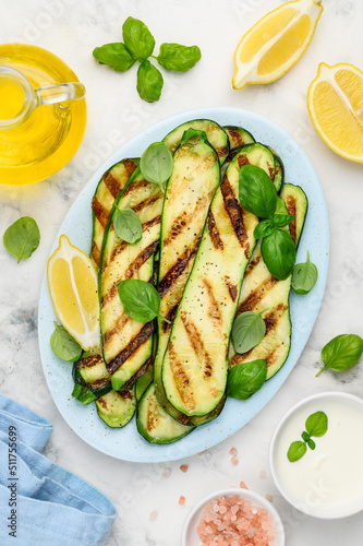 Grilled zucchini slices in a blue plate on a marble  background. Healthy summer veggie food. Top view