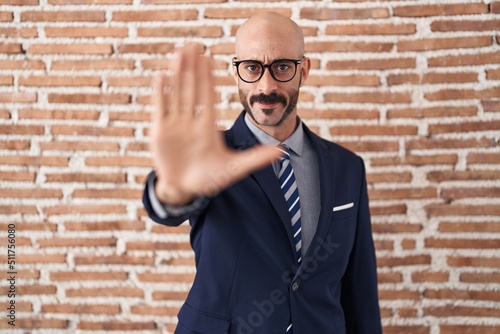 Bald man with beard wearing business clothes and glasses doing stop sing with palm of the hand. warning expression with negative and serious gesture on the face.