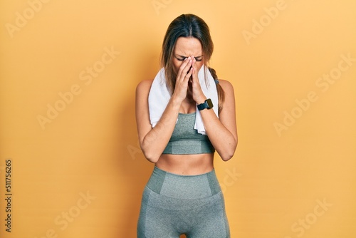 Beautiful hispanic woman wearing sportswear and towel with sad expression covering face with hands while crying. depression concept.