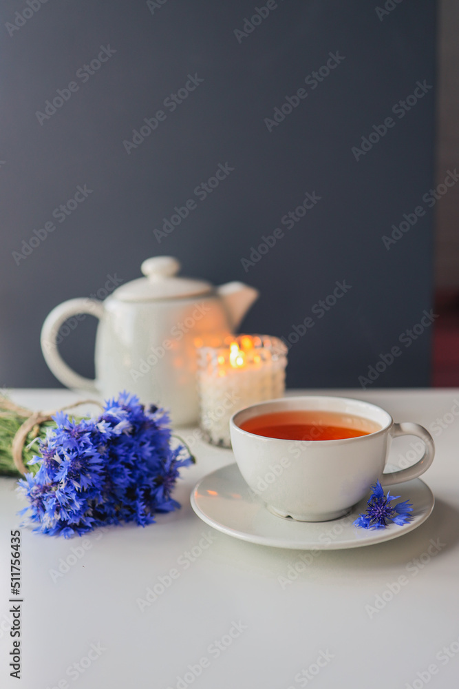 Tea, teapot, candle and a bouquet of cornflowers on the table Tea, teapot, candle and a bouquet of cornflowers on the table