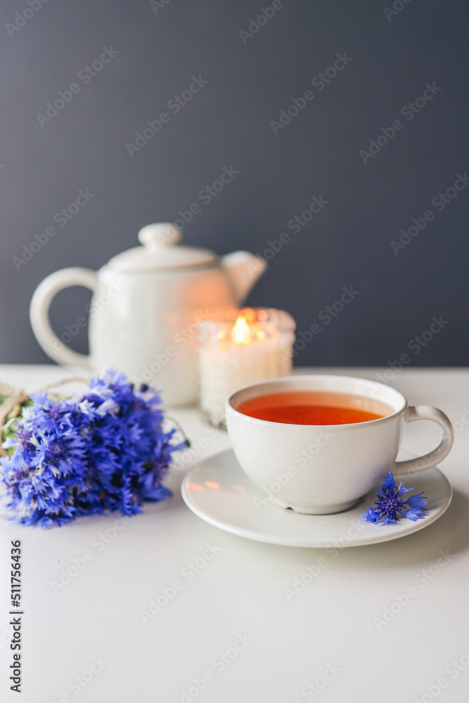 Tea, teapot, candle and a bouquet of cornflowers on the table Tea, teapot, candle and a bouquet of cornflowers on the table