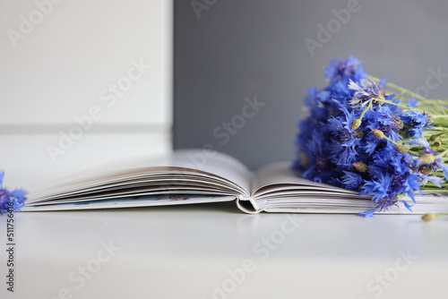 A bouquet of cornflowers and a book on the table