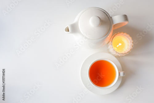 Tea  teapot and candle on a white background. Cozy warm photo