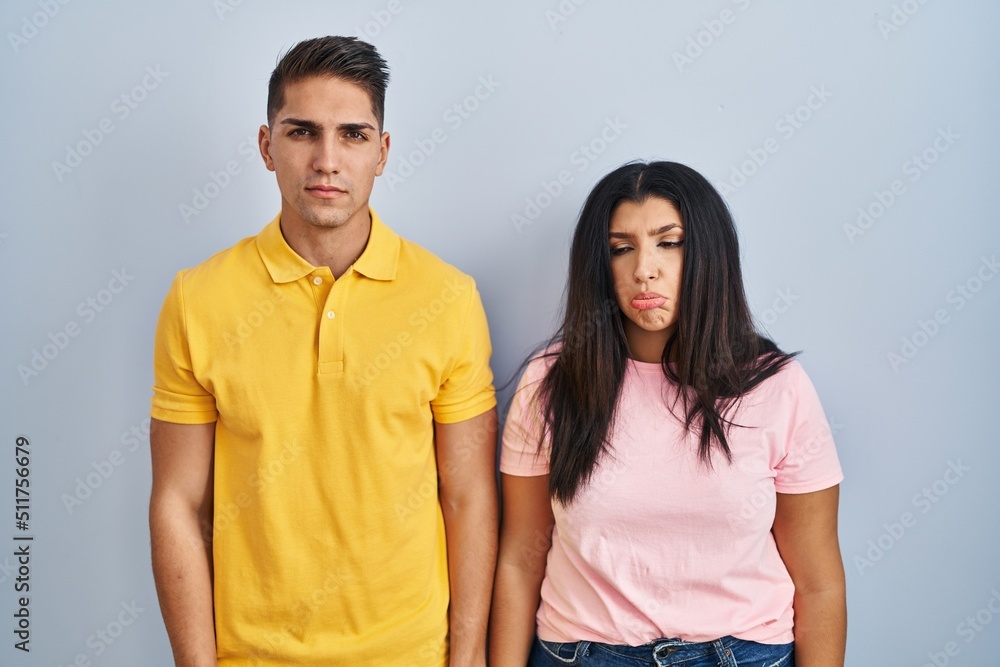 Fototapeta premium Young couple standing over isolated background depressed and worry for distress, crying angry and afraid. sad expression.