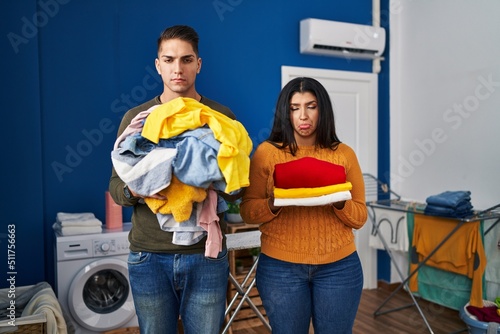 Young couple holding laundry dirty and clean laundry depressed and worry for distress, crying angry and afraid. sad expression.