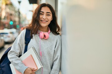 Young middle east student girl smiling happy holding book at the city.