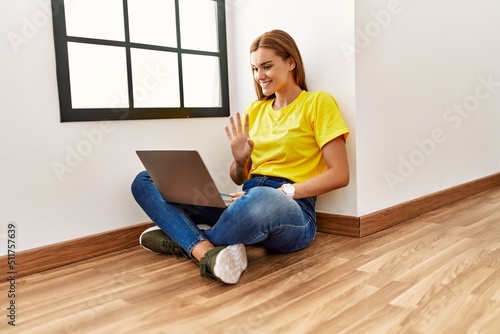 Young woman having video call sitting on floor at empty room photo