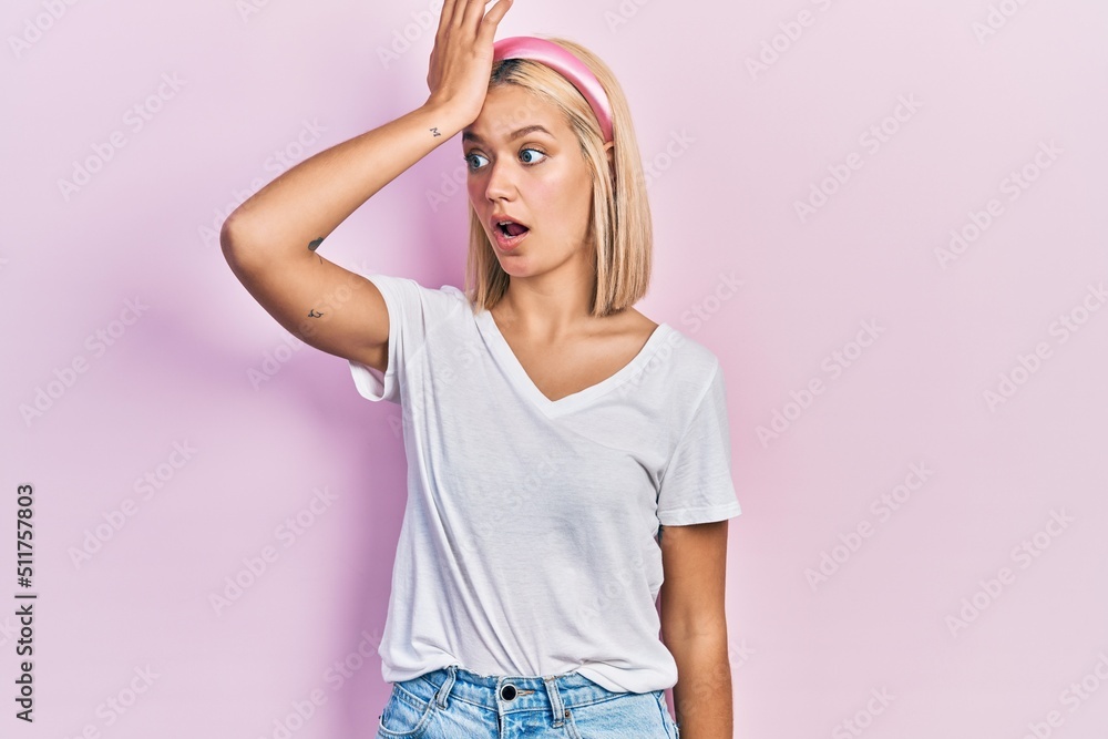 Beautiful blonde woman wearing casual white t shirt surprised with hand on head for mistake, remember error. forgot, bad memory concept. Beautiful blonde woman wearing casual white t shirt surprised with hand on head for mistake, remember error. forgot, bad memory concept.