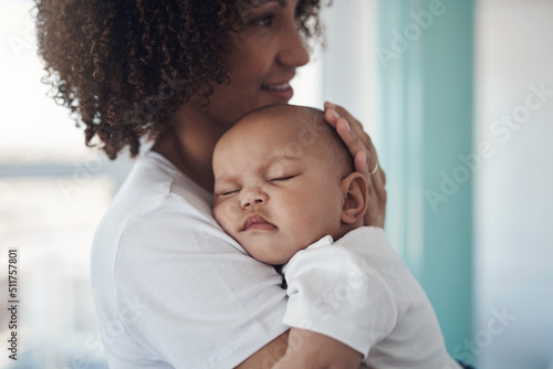 Shh, mommy is here. Shot of an adorable baby girl sleeping peacefully in her mothers arms at home.