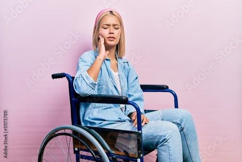 Beautiful blonde woman sitting on wheelchair touching mouth with hand with painful expression because of toothache or dental illness on teeth. dentist